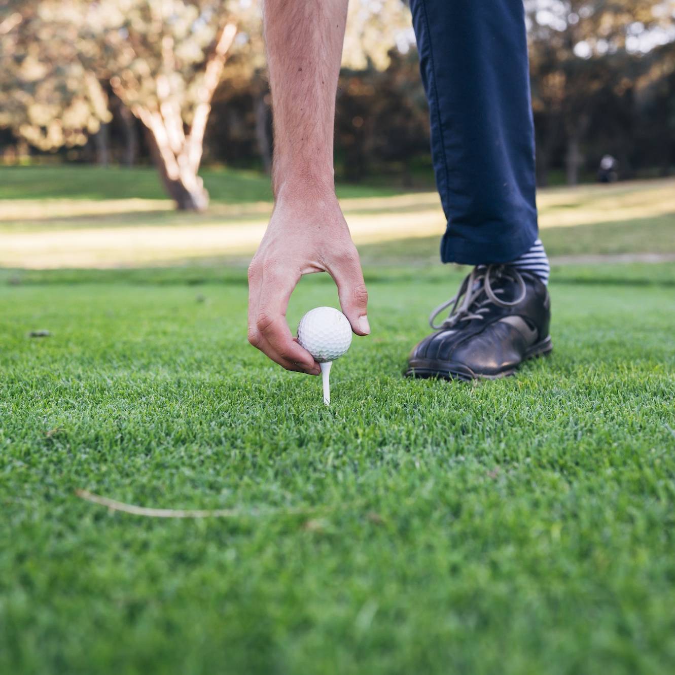 Golfer puts the golf ball on a tee