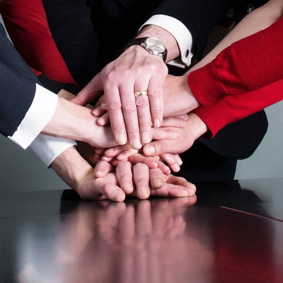 Business Team Putting Their Hands On Top Of Each Other At Meeting Table